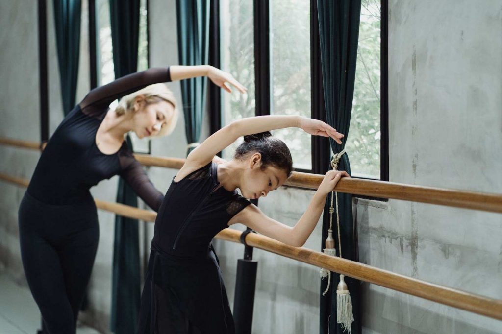 Two girls stretching for ballet dance songs for kids