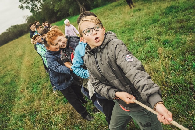 Young children playing tug of war at summer camp kids