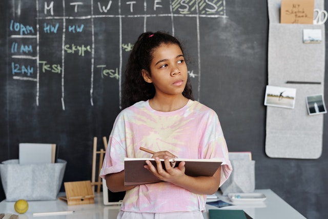 Young girl holding brown notebook journal prompts for kids