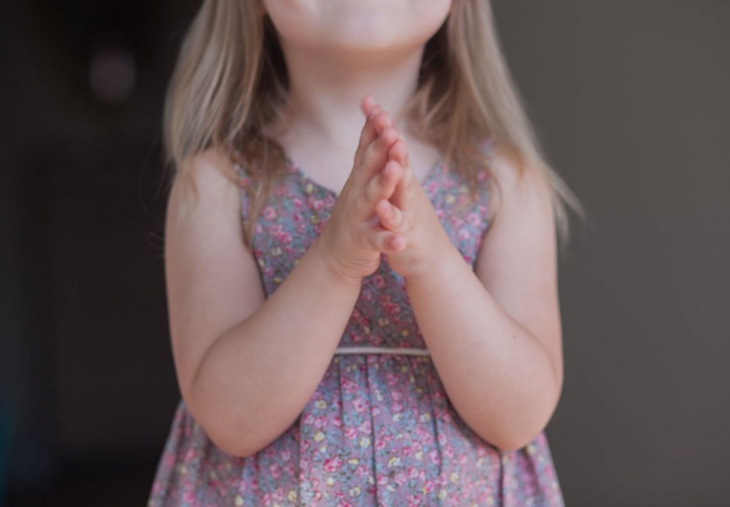 Young girl praying with folded hands prayers for children