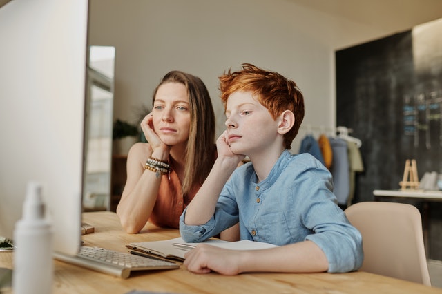 Image of a kid and parent seeing towards a desktop screen
