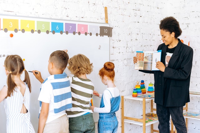 Teacher holding pamphlet with students in class