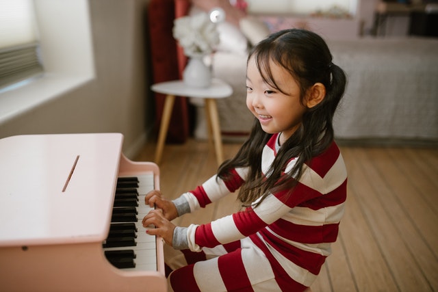 A Girl Playing Piano and Smiling