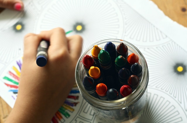 Kid filling coloring book with crayons