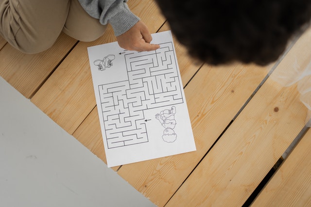 Child solving maze printed on paper at home