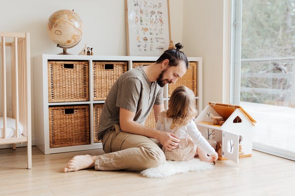 Father and daughter playing with a dollhouse together