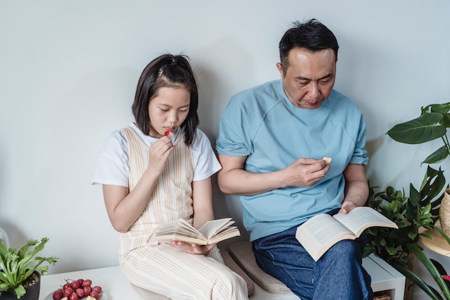 Father and daughter reading book together eating berries