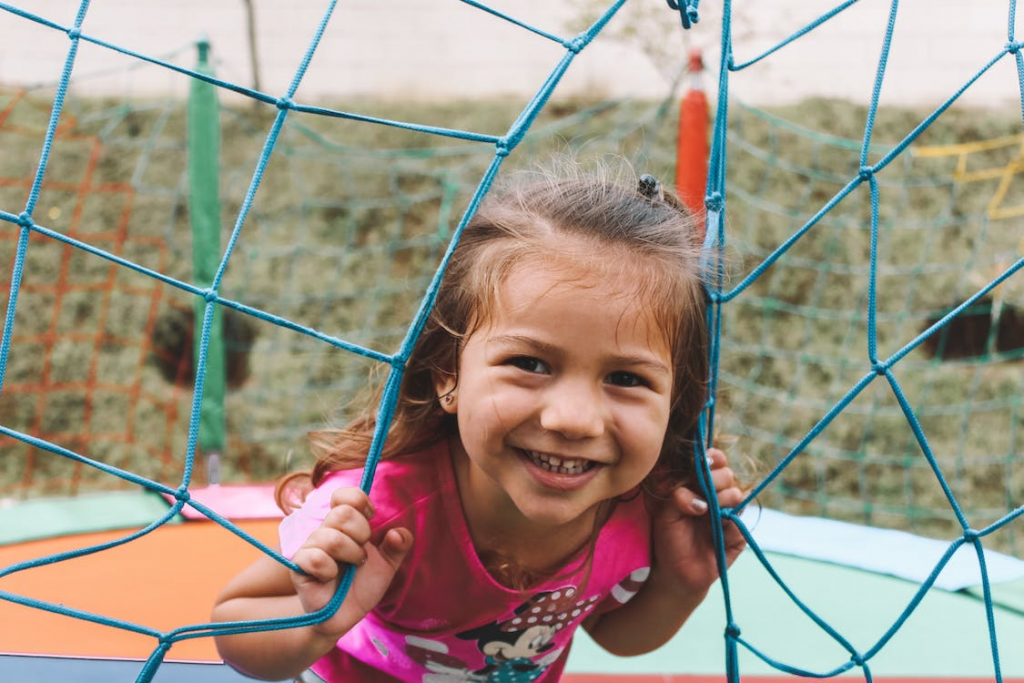 Young girl playing outside looking through net