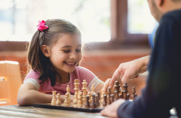 Young girl playing chess with father