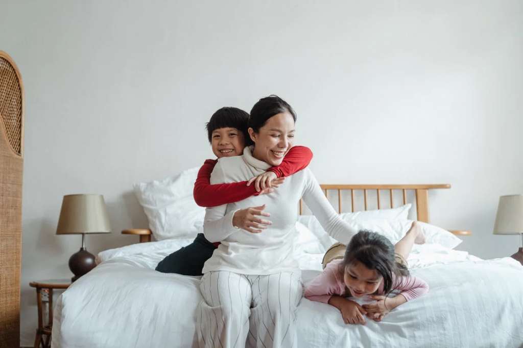 Mother playing with her kids on bed
