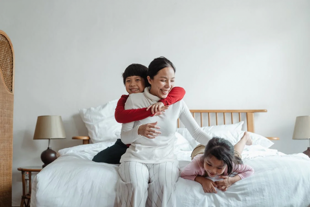motherandkidsareplayinginpicture Mother playing with her kids on bed