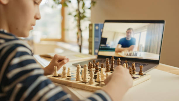 Young boy playing chess with man on video call
