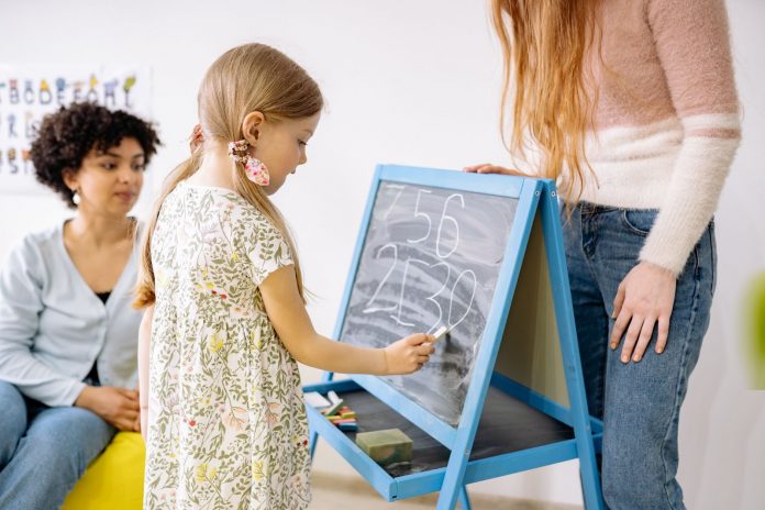 Young girl writing with chalk on board