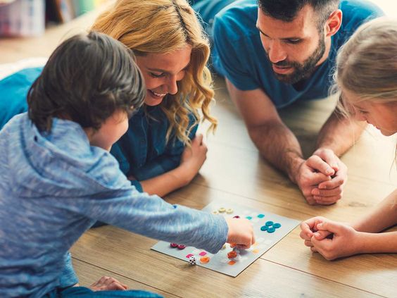 Parents playing board game with kids sitting on floor