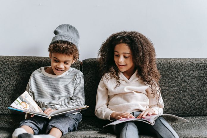 Two kids reading picture books on a sofa