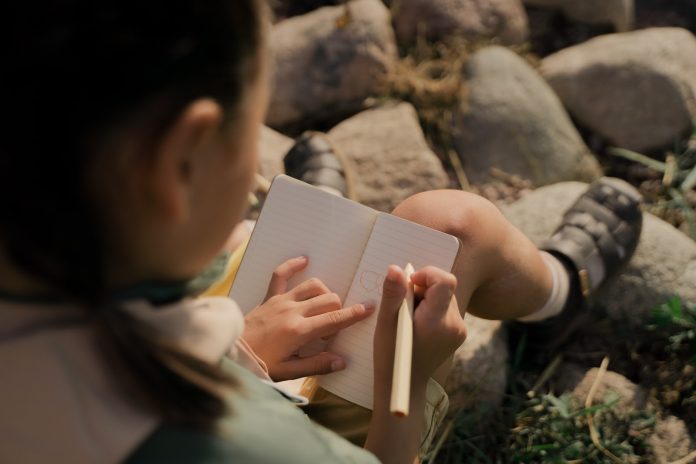 Young girl taking notes on how to improve handwriting