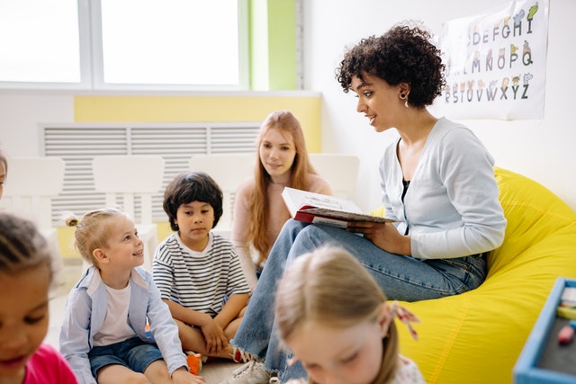 Woman reading book to children in class