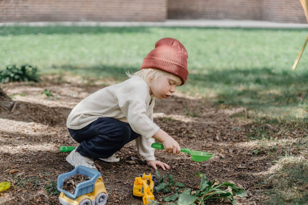 Young child playing with gardening tools in garden