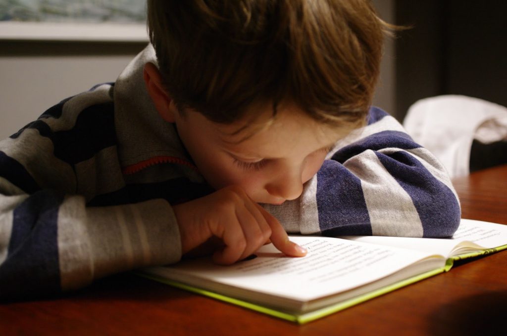 Young child reading a book and tracing words with their finger