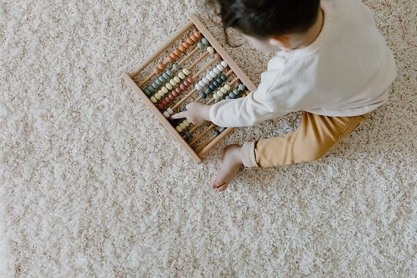 Young child sitting on rug playing with abacus