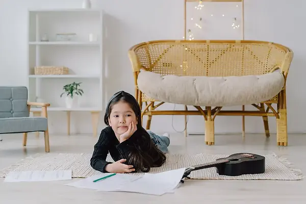 Small girl lying on a rug in a living room with some sheets of paper