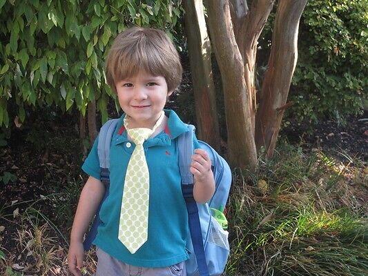 A child standing with their school bag on first day of school