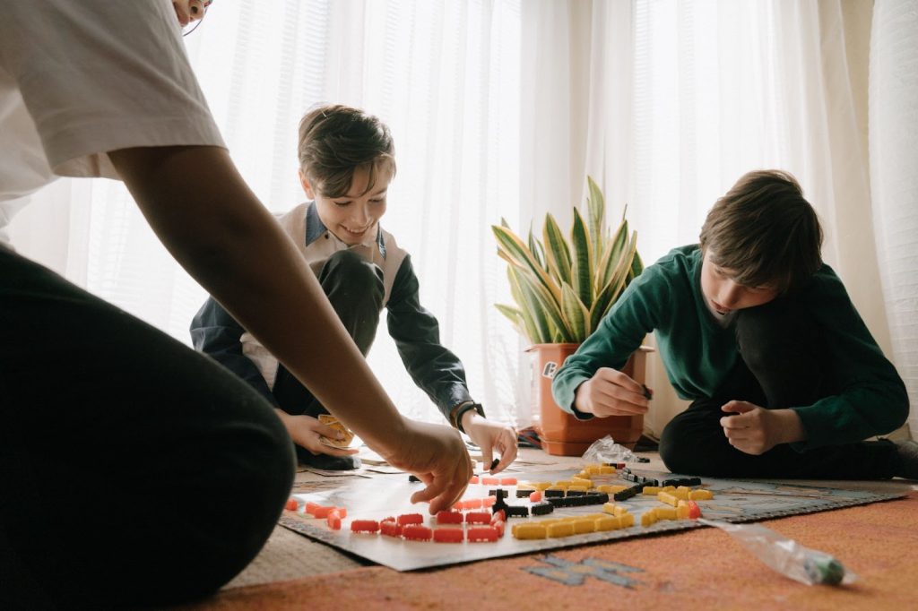 Young boys sitting on the floor, playing a board game
