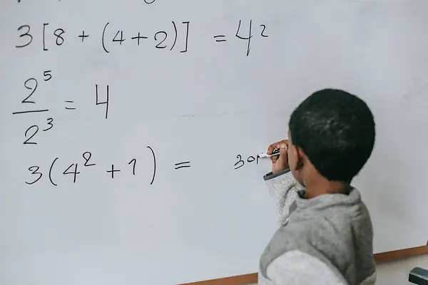 Boy writing math solutions on a whiteboard