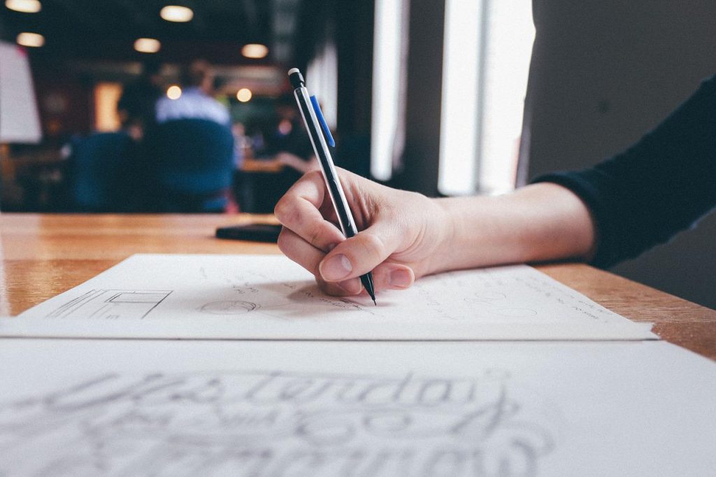 A hand holding a pen over a sheet of paper on a table