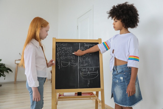 Young girls solving a math problem on a blackboard