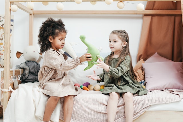Two young girls playing with stuffed toys