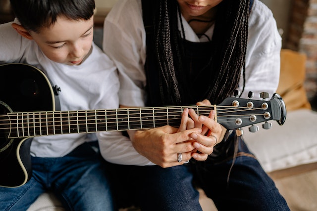 Woman teaching a young child how to play guitar