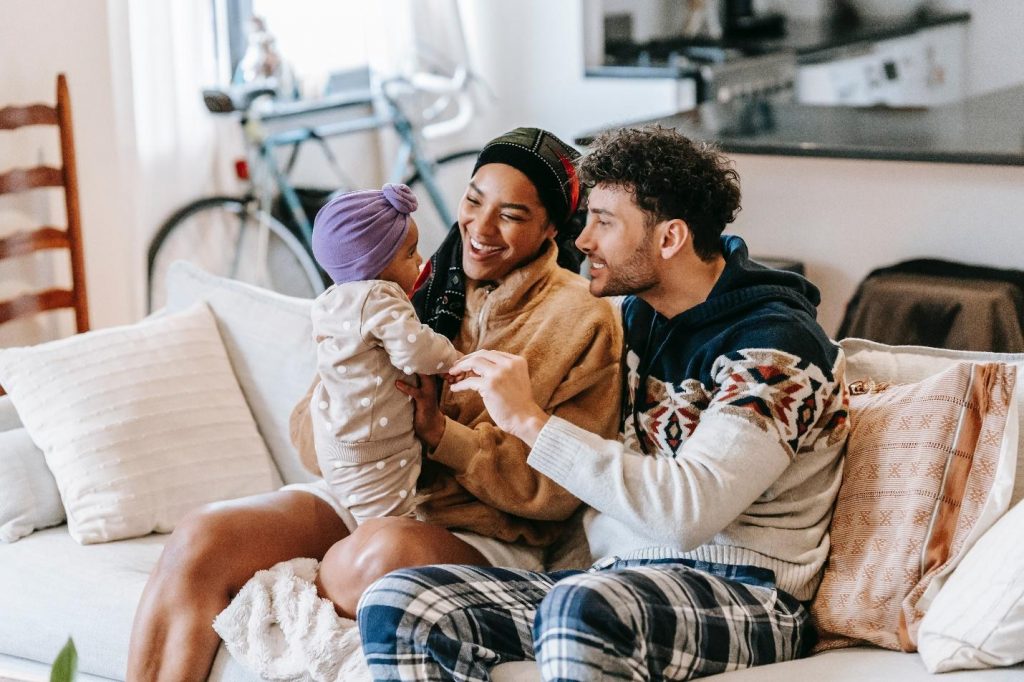 Parents smiling and playing with a little girl on the sofa