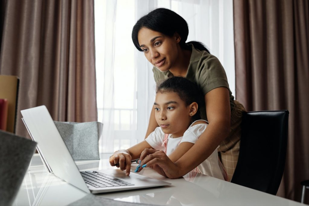 A mother helping her child with something on a laptop