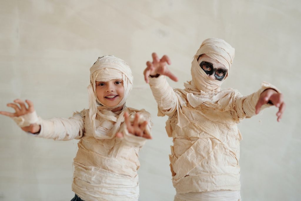 Two kids pose in mummy costumes