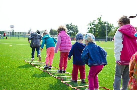 Kids jumping through tracks on a sports field