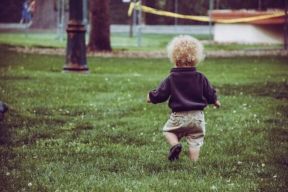 Toddler running through a park