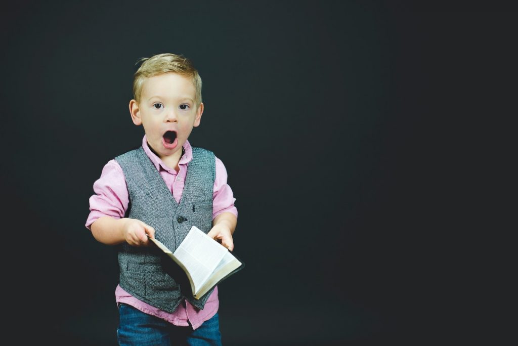 Surprised young boy holding a book