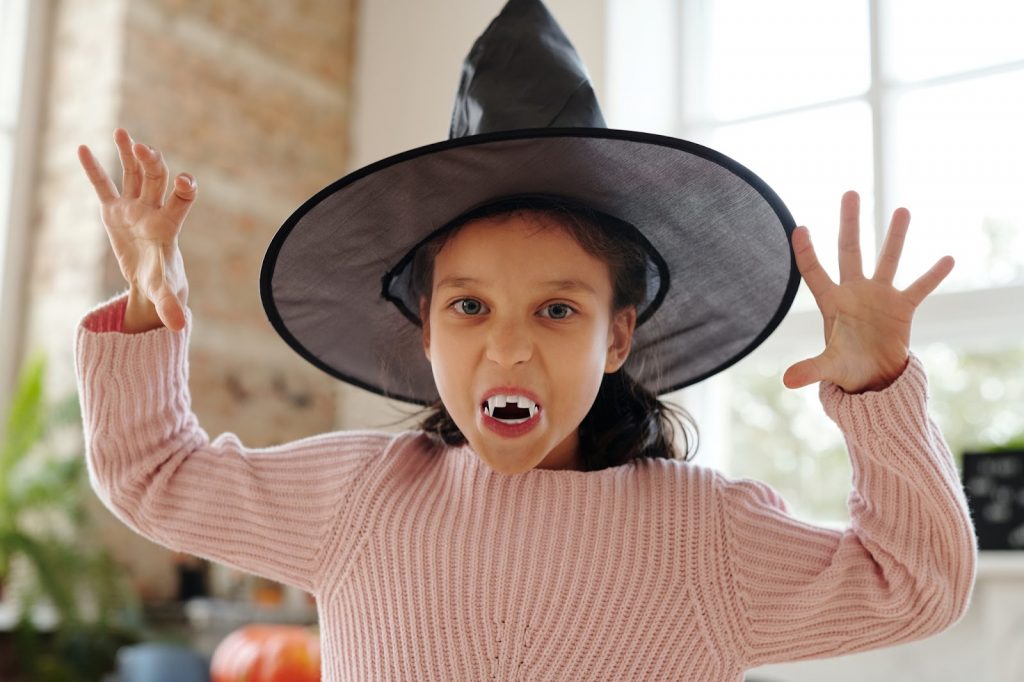 Girl poses with vampire fangs and a witchs hat