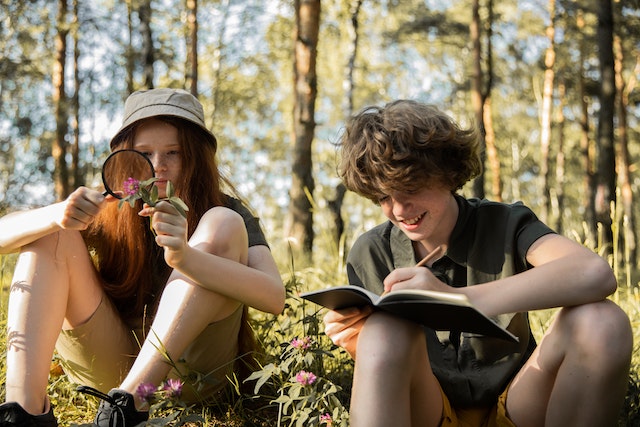 Young boy and girl sitting in the woods on a nature walk