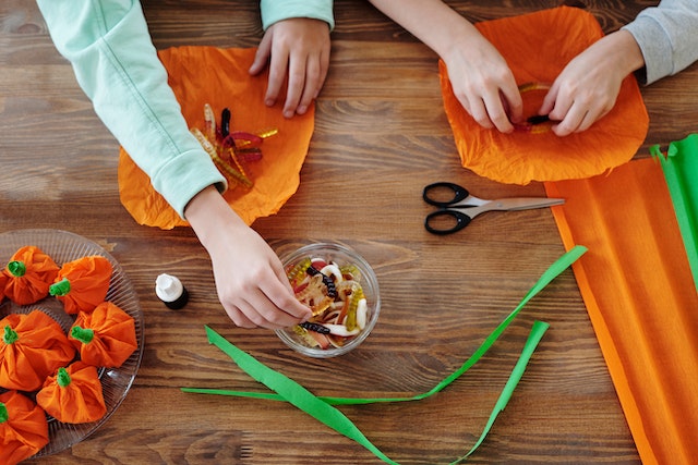 Children wrapping candies in an orange paper