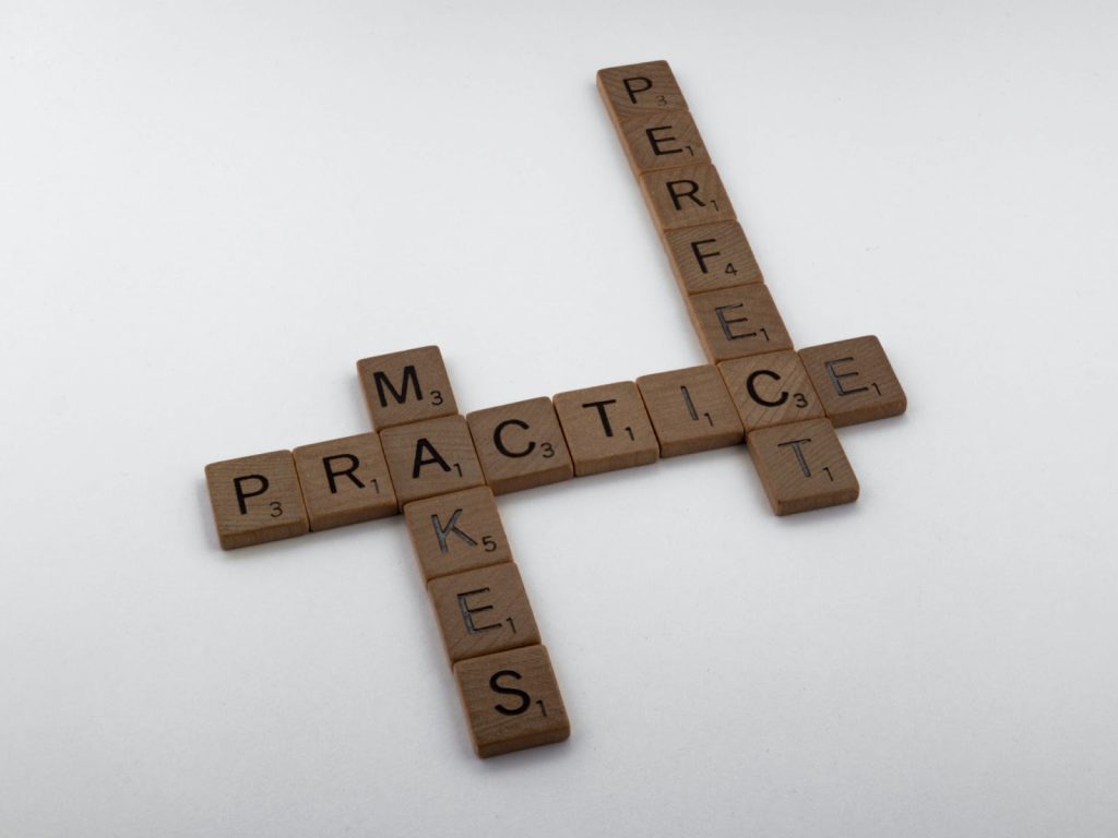 Crossword pieces aligned to read “practice makes perfect”