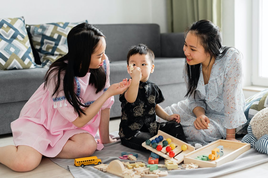 Two women playing with child on carpet holding abacus