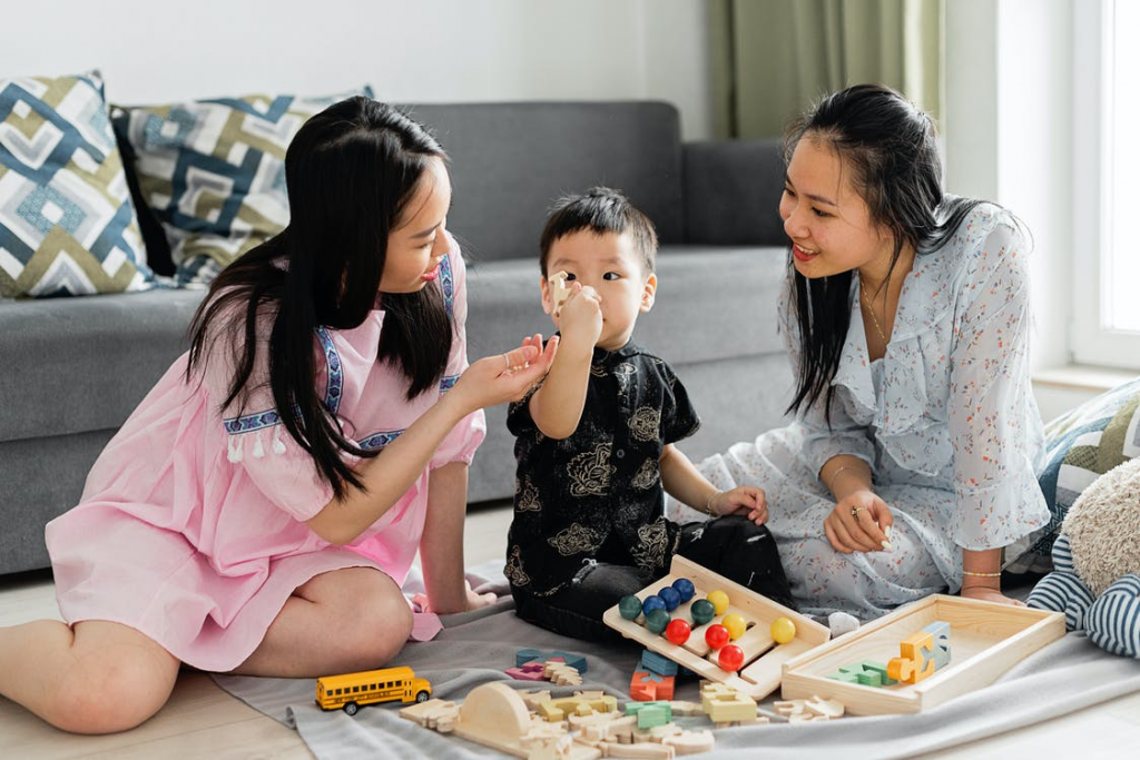 teachingmathskillstoelementaryschoolstudentsintheclassroom Two women playing with child on carpet holding abacus