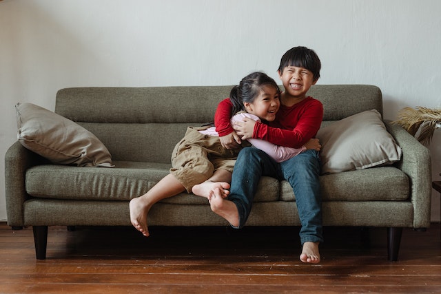 Brother and sister playing on the sofa and laughing