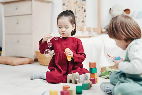 Young kids playing blowing bubble and playing with blocks