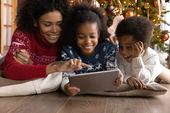 Family playing on a tab in front of a Christmas tree
