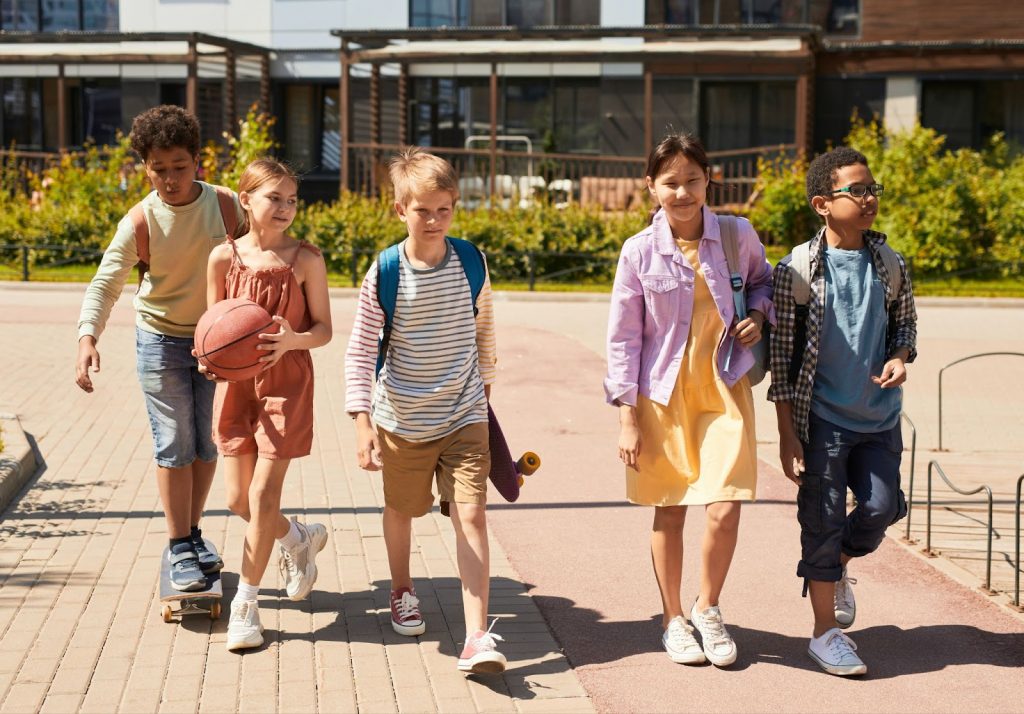 A group of children walking outdoors on the sidewalk