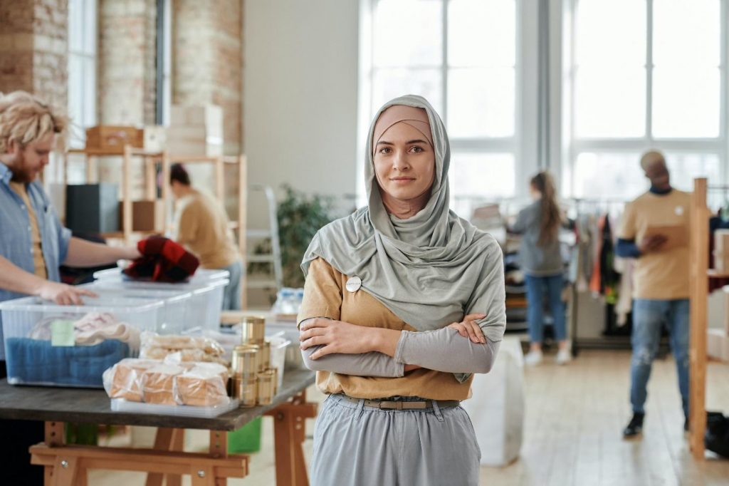 Woman wearing a hijab with people sorting items in the background