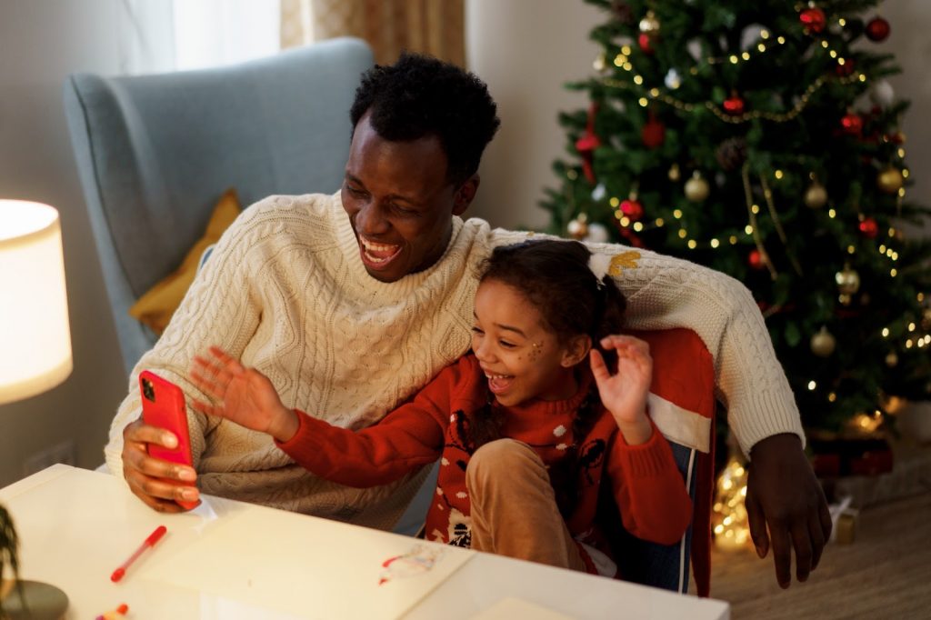 A father and daughter laugh together as they stare into his phone